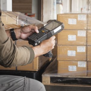 Warehouse worker holding barcode scanner. Computer equipment for warehouse inventory management. Storage warehouse.